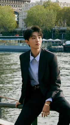 a young man in a suit sitting by the water