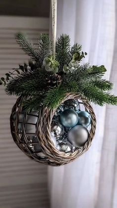 a christmas ornament hanging from a window sill with ornaments and greenery