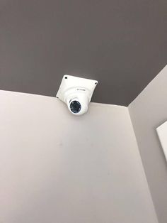 a security camera mounted to the ceiling in a room with gray walls and white trim