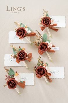 four boutonnieres with flowers on them sitting on top of a white table