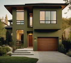 a green house with two garages and steps leading up to the front door is shown