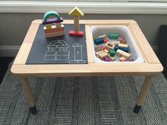 a child's play table with toys on it and a chalkboard in the middle