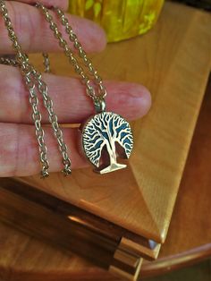 a person holding onto a necklace with a tree on it