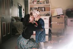 a woman sitting on the floor eating something out of her mouth while standing next to another woman