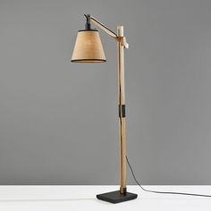 a lamp that is on top of a white table next to a gray wall and floor