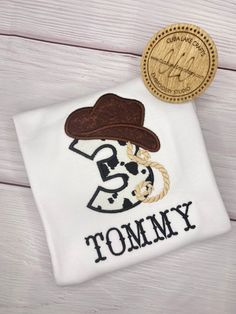 a white t - shirt with a brown cowboy hat and the words tommy on it