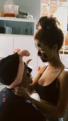 a woman is getting her makeup done by a man in a black tank top and bunny ears