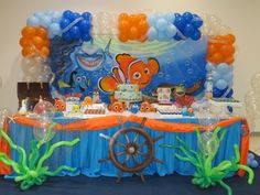 an under the sea themed birthday party with balloons, decorations and decorating items on a blue table cloth