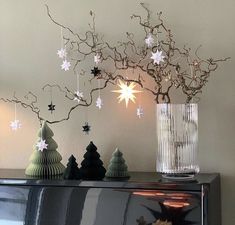 christmas decorations are displayed on top of a dresser in front of a tree with white snowflakes hanging from it