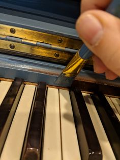 a person is writing on the keys of an old piano with a pen in their hand