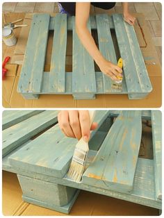 a person painting the bottom of a wooden bench with blue paint and a yellow brush