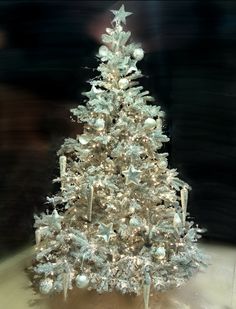 a white christmas tree with silver ornaments on it