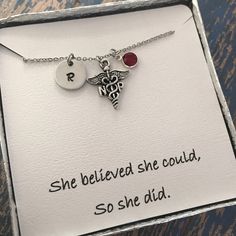 a medical necklace with two charms on it in a box that says she believed she could, so she did