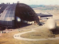 an aerial view of a large airplane hangar in the middle of a field with several planes parked around it