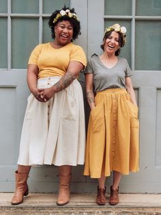 two women standing next to each other in front of a door with flowers on their head