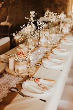 a long table is set up with white and pink flowers in vases on it