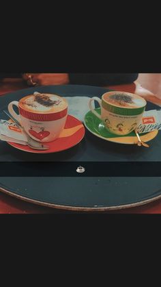 two coffee cups sitting on top of a blue plate