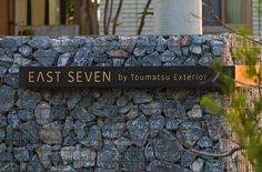 a stone wall with a sign that says east seven by tomasu exterior