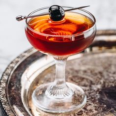 a glass filled with liquid sitting on top of a metal tray