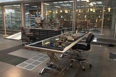 an office with lots of bookshelves and desks in front of glass windows