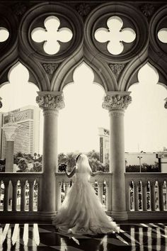 a bride standing in front of an ornate archway with columns and arches on either side