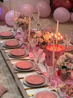 a table set with pink plates and candles