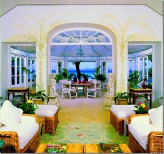 a living room filled with lots of furniture next to a dining table and ocean view