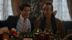 two men standing next to each other in front of a table with christmas decorations on it