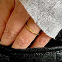 a woman's hand with a gold ring on her finger and black leather pants