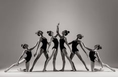 five ballerinas in black and white pose for a photo