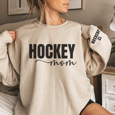 a woman wearing a hockey mom sweatshirt with her hands on her hips and looking off to the side