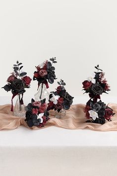 three vases filled with flowers on top of a white tablecloth covered table cloth