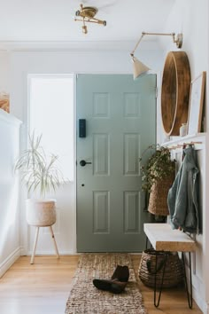 a green door in a white room next to a wooden bench and potted plant