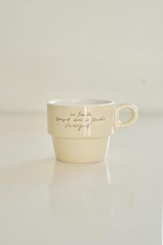 a white cup with writing on it sitting on a table