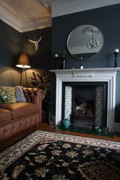 a living room with a couch, fireplace and mirror on the wall next to it