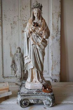 a statue of the virgin mary holding a flower