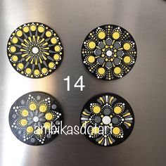 four black and yellow coasters sitting on top of a metal surface with white dots