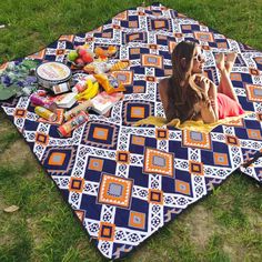 a woman laying on top of a blue and orange blanket next to a bowl of fruit