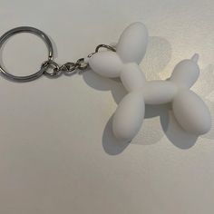 a white keychain shaped like a poodle on a white surface with a silver ring