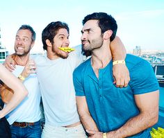 four men with toothbrushes in their mouths are posing for a photo while standing next to each other