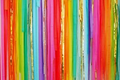 multicolored streamers hanging from the ceiling in front of a wall with gold foil