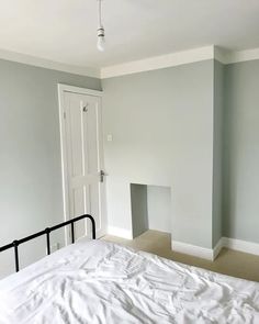 an empty bedroom with a white bed and fireplace