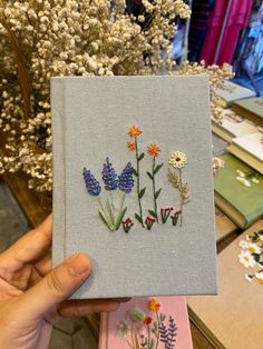 a hand holding up a small book with flowers on it