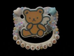 a brooch with a teddy bear on it's back and words around it