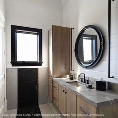 a bathroom with two sinks and a round mirror