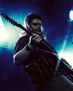 a man holding a guitar while standing on stage