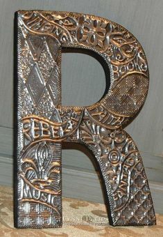 the letter p is made out of metal and has intricate designs on it's sides