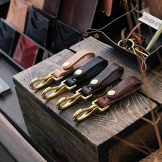 four pairs of scissors sitting on top of a wooden box next to other leather items