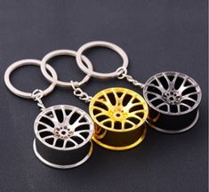 four wheel key chains on a black surface with gold rims and silver spokes