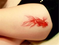 a woman's thigh with a goldfish tattoo on it